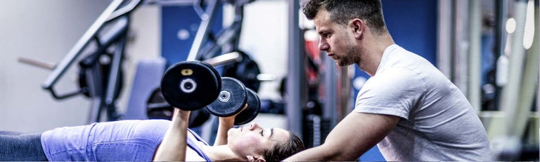 Client and trainer lifting weights at the gym