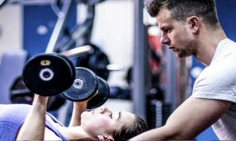 Client and trainer lifting weights at the gym