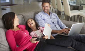 Happy family on sofa with laptop and tablet