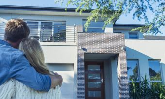 Couple standing in front of new home.