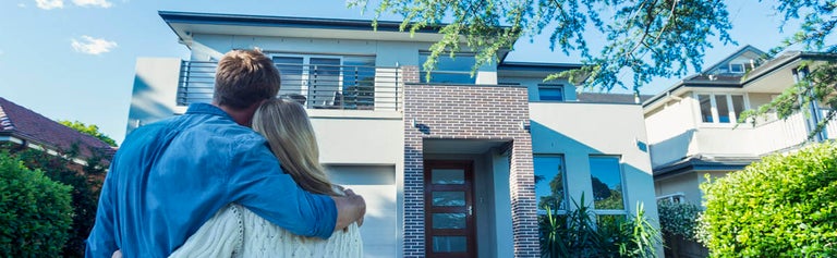 Couple standing in front of new home.