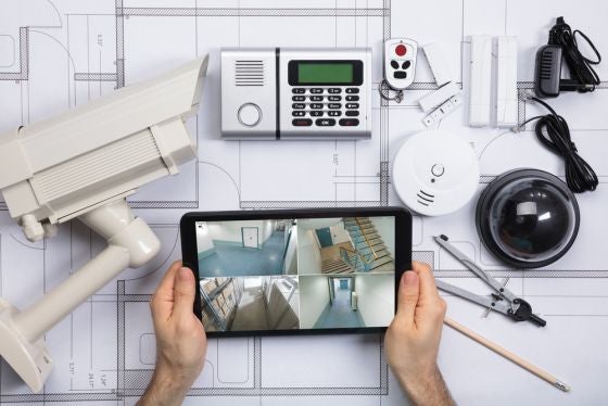 Close-up Of A Person Watching Footage On Digital Tablet With Security Equipments On Blueprint